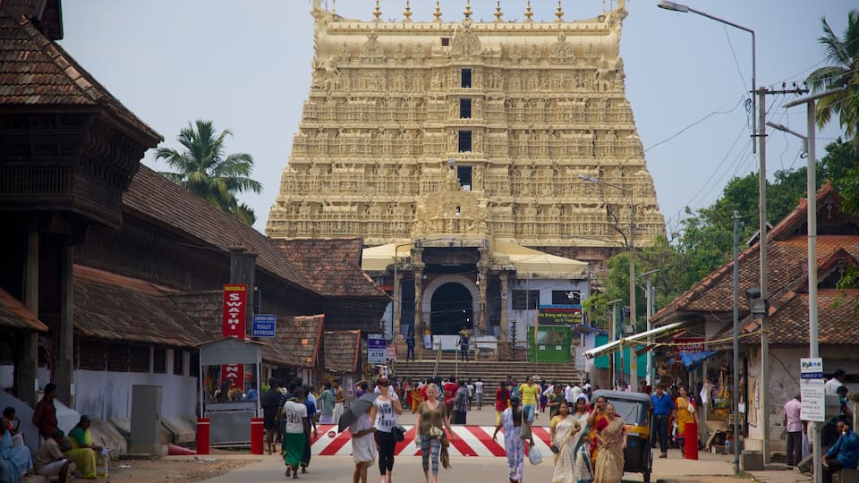 A large temple with intricate carvings, a busy street with people and shops, and traditional buildings.