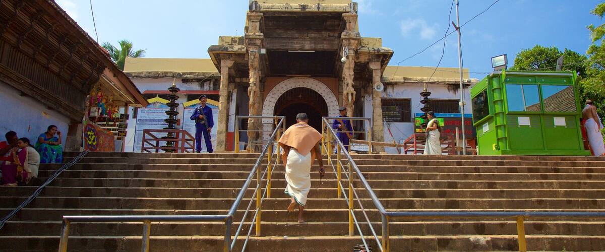 A temple entrance with a golden spire, steps leading up to it, and a green structure to the right.