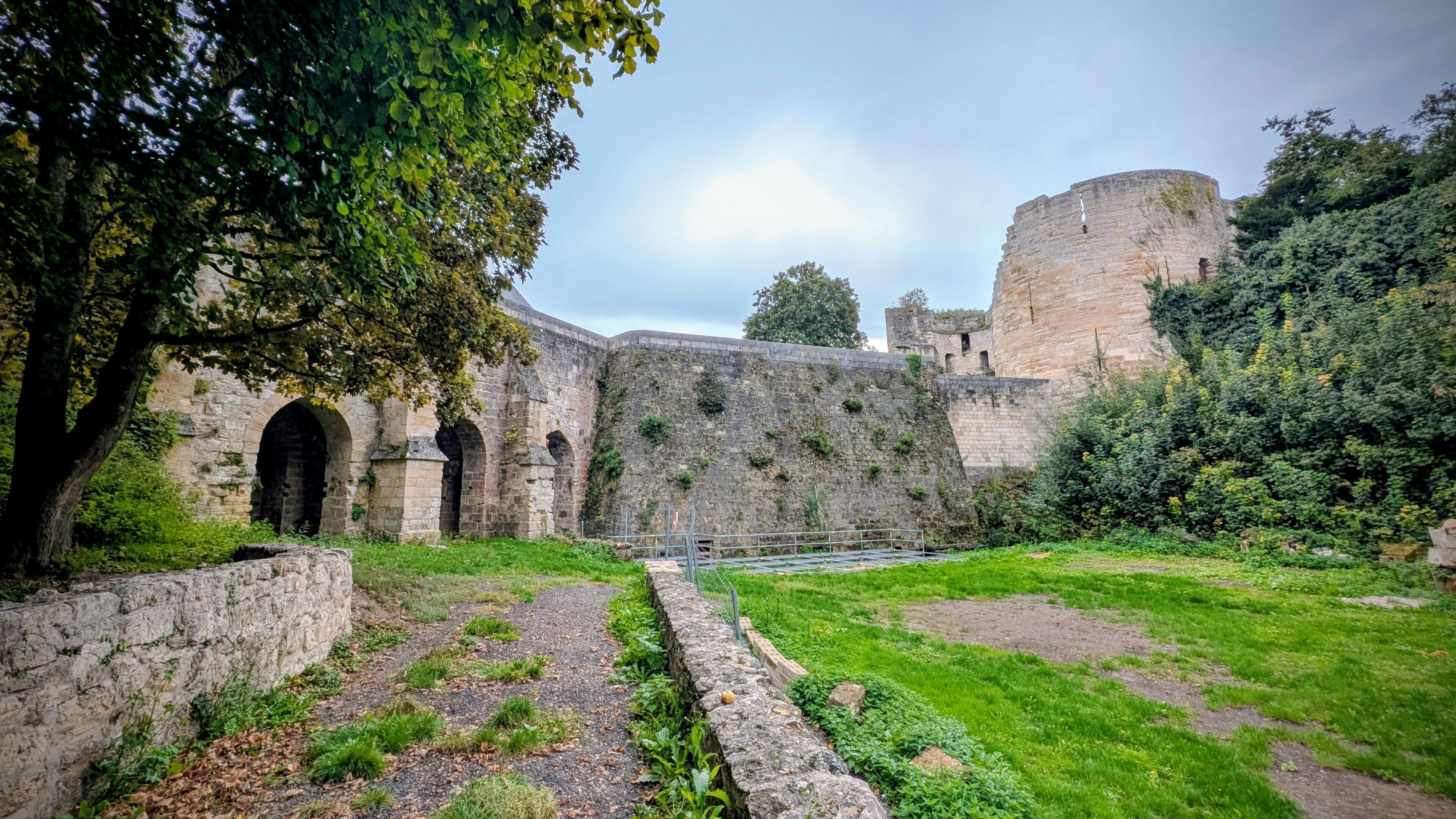 A historic stone wall with arches and a moat.