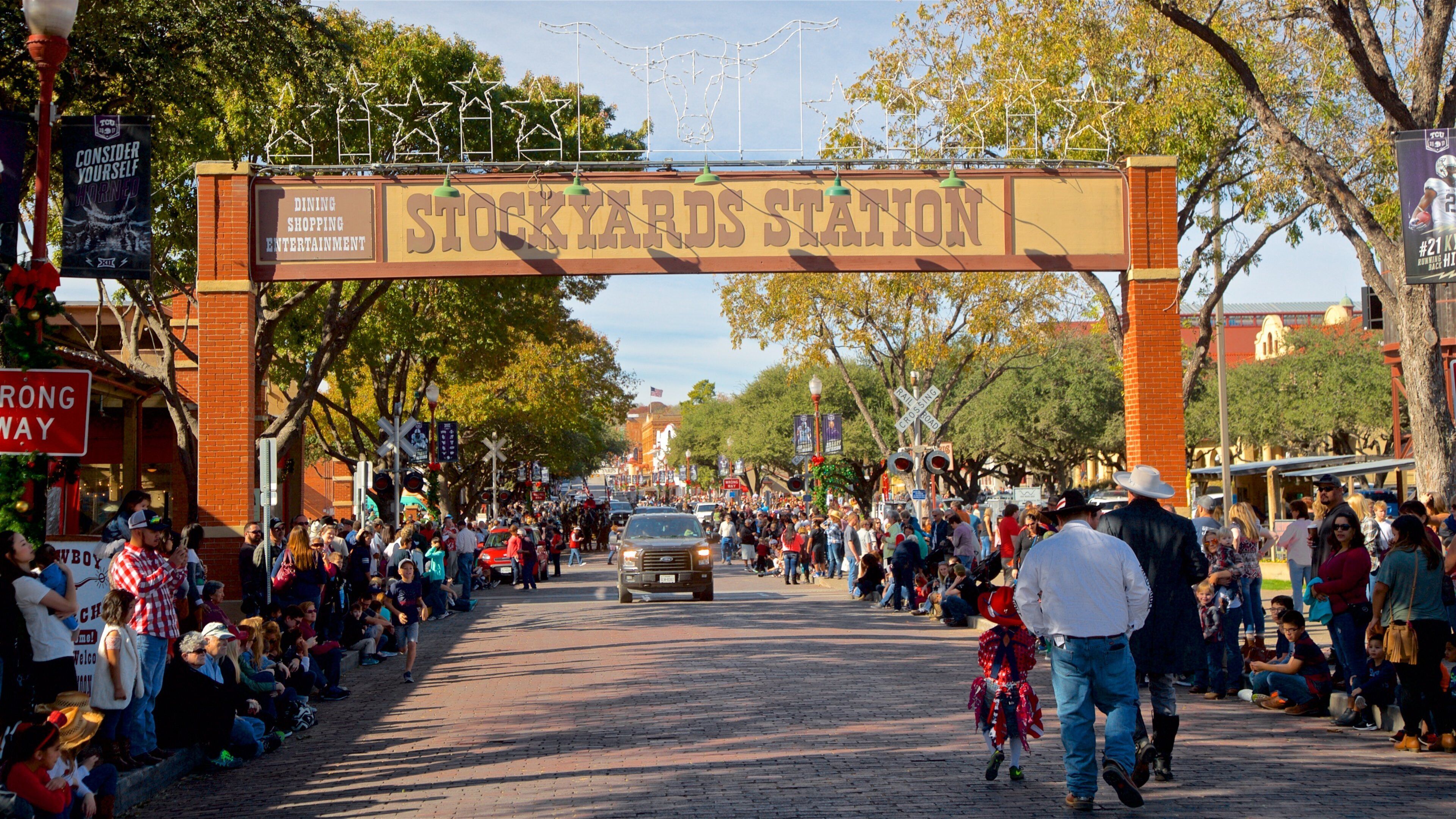 Eine belebte Straße mit einem großen Bogen, der "Stockyards Station" zeigt, und einer Menschenmenge.