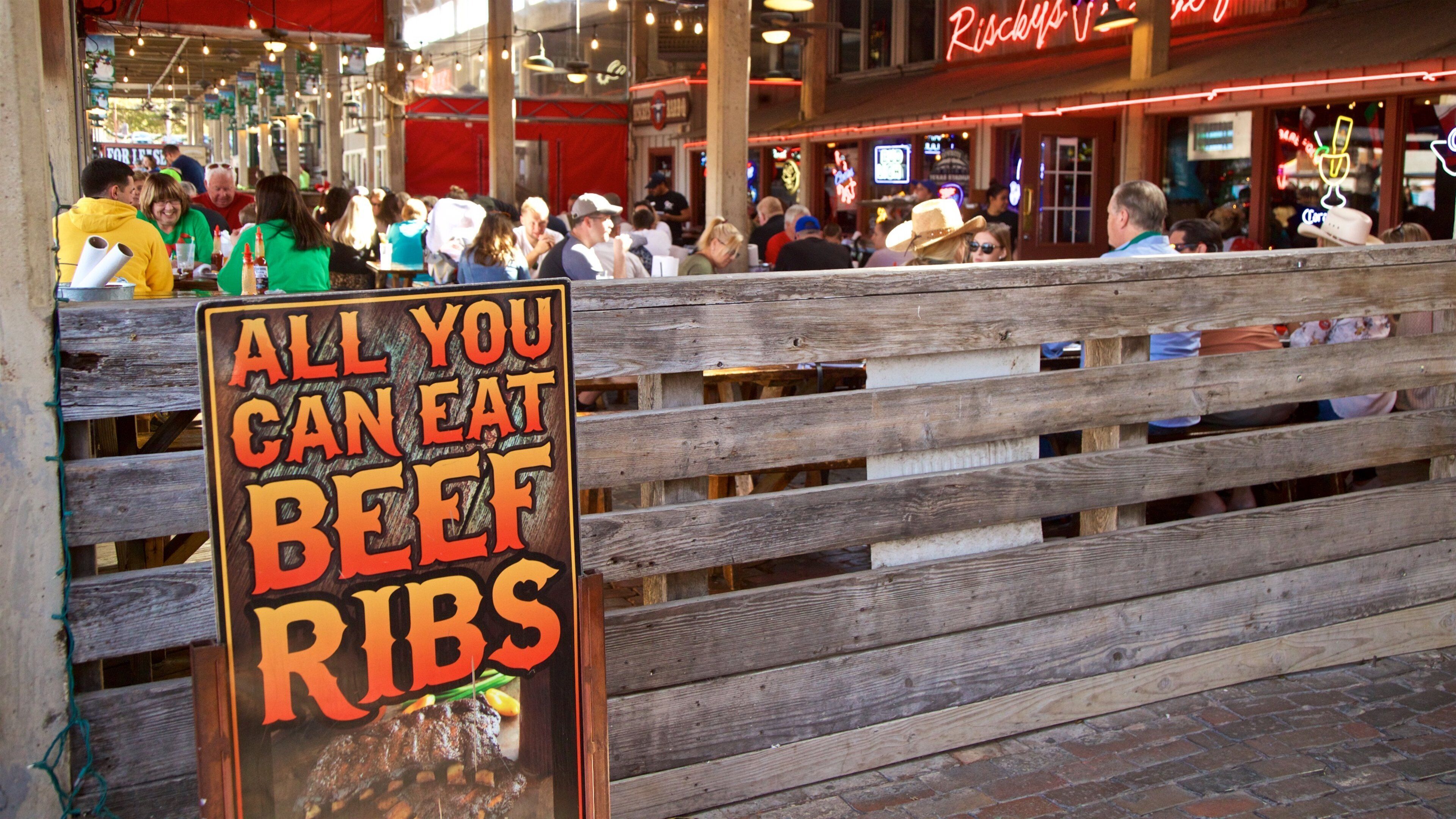 Fort Worth Stockyards showing outdoor eating and signage as well as a small group of people