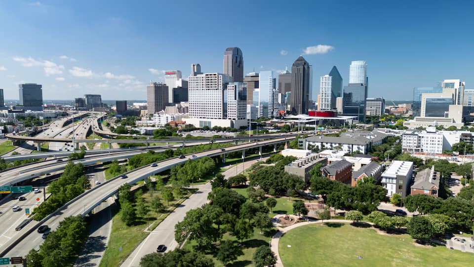 Dallas skyline with highway and greenspace of Griggs park with State Thomas Uptown neighborhood on beautiful day.