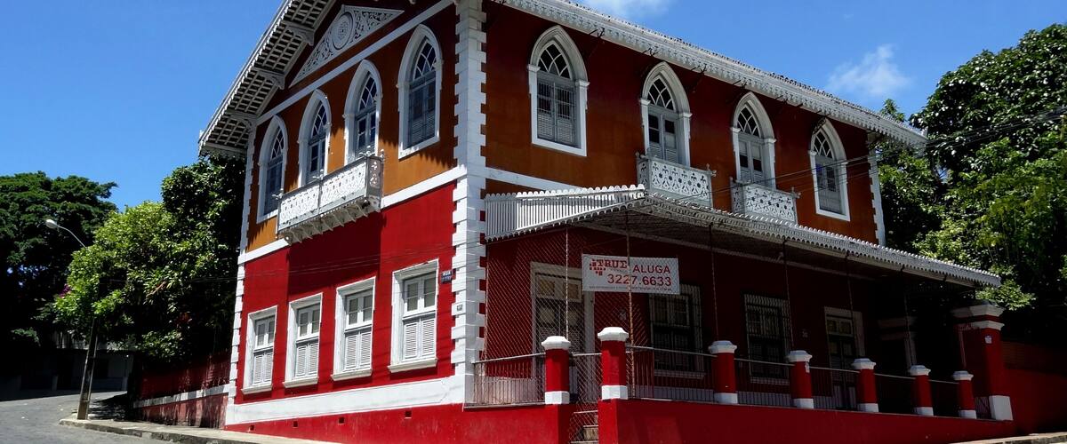 A red and white colonial-style building with arched windows and a balcony.