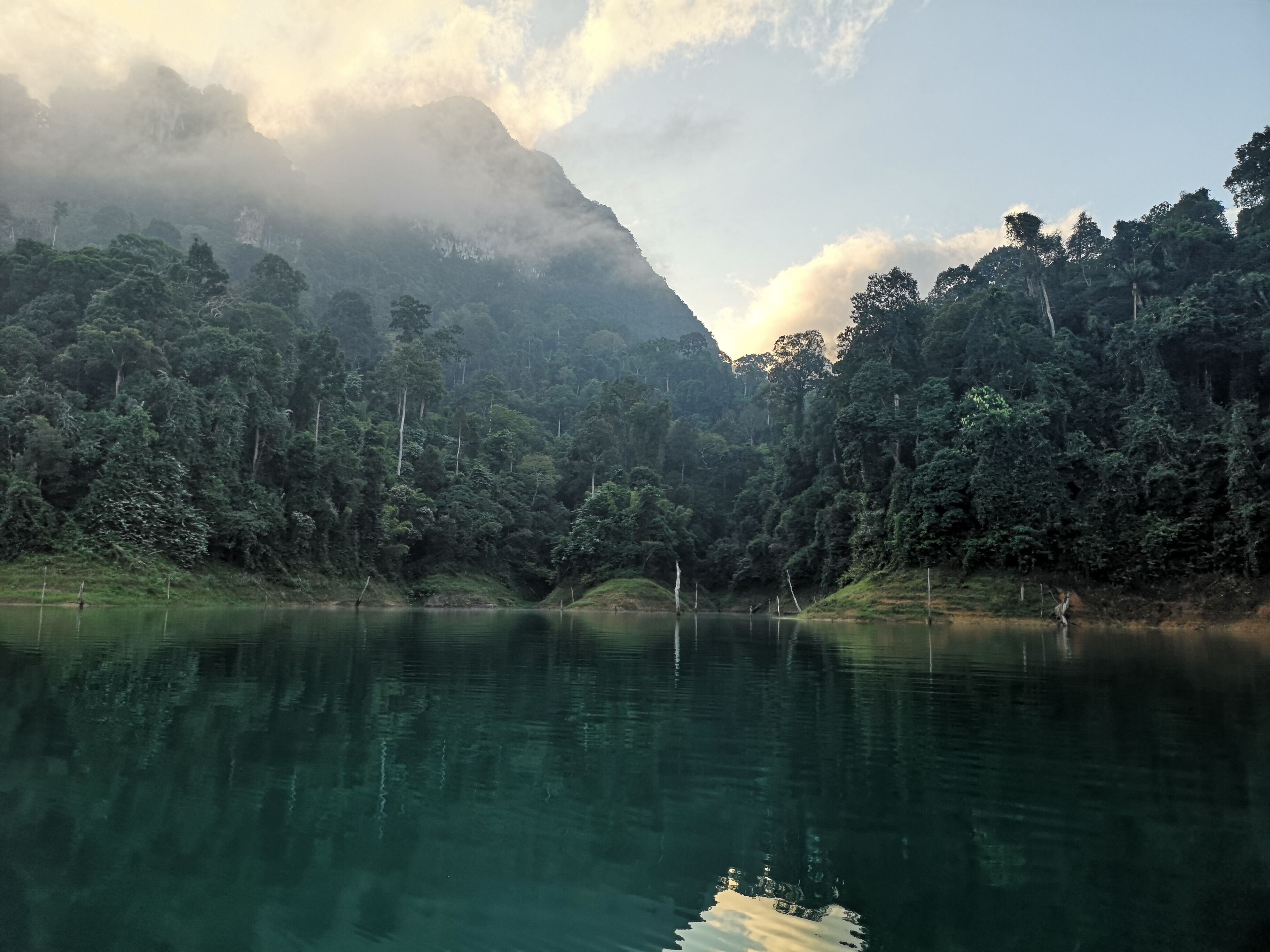 A calm lake surrounded by dense forest and a mountain in the background.