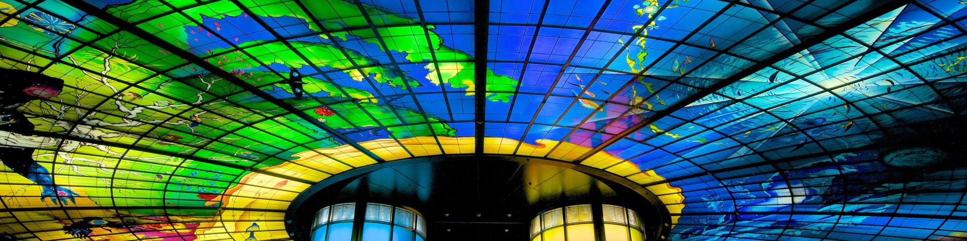 Un techo de vitrales coloridos con un diseño de cuadrícula y diversos motivos abstractos.