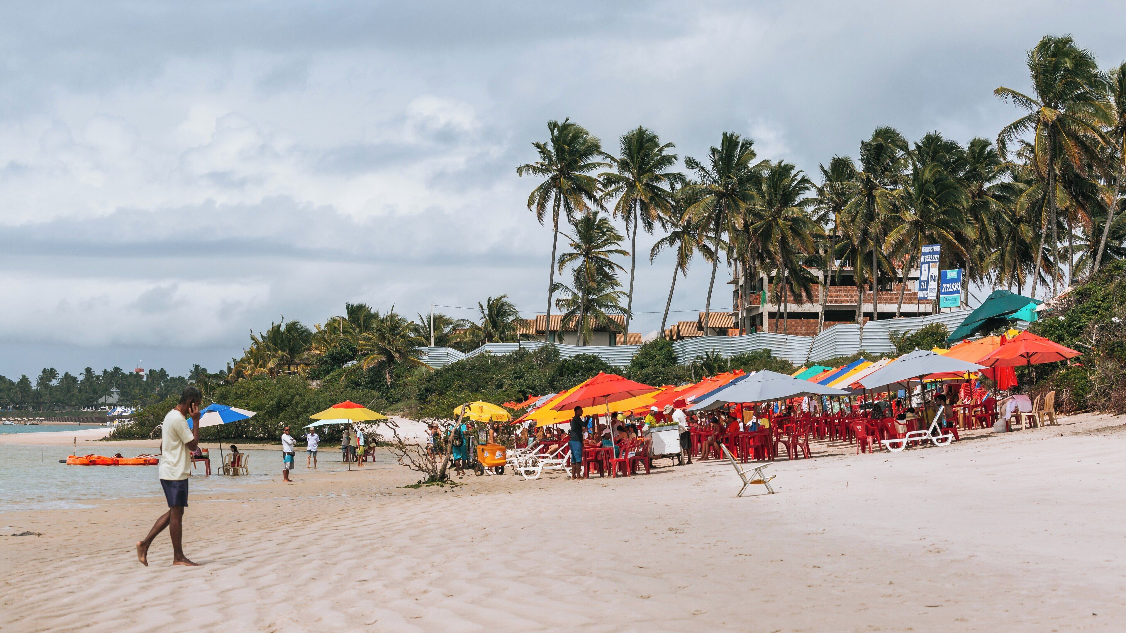 Muro Alto Beach offers vibrant umbrellas and a lively atmosphere in Porto de Galinhas, Ipojuca, Pernambuco, Brazil on a cloudy day