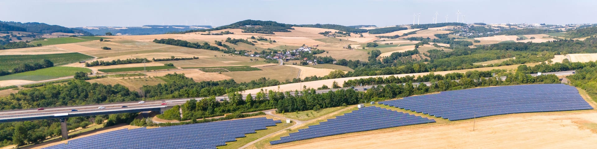 A solar farm with wind turbines in the background.
