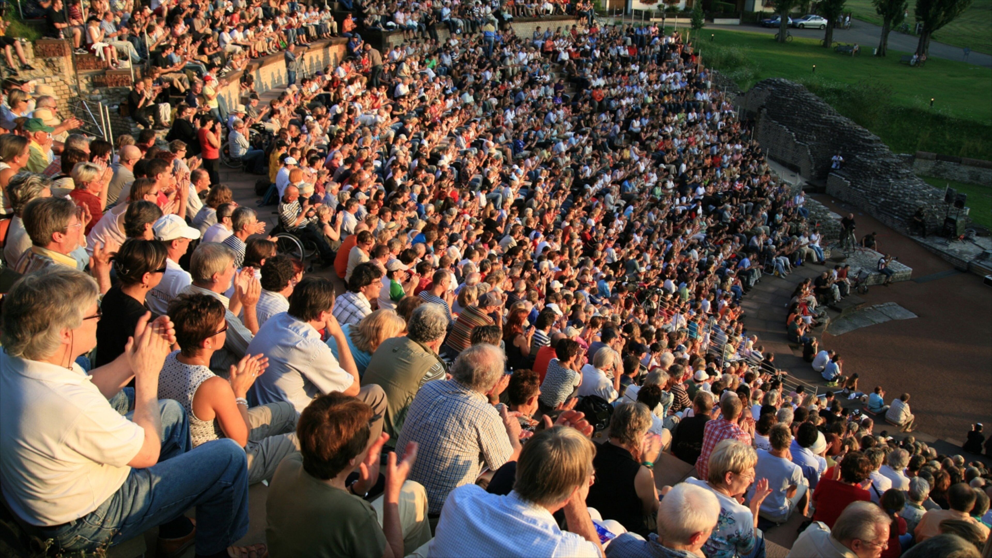 A large crowd of people seated in an outdoor amphitheater.