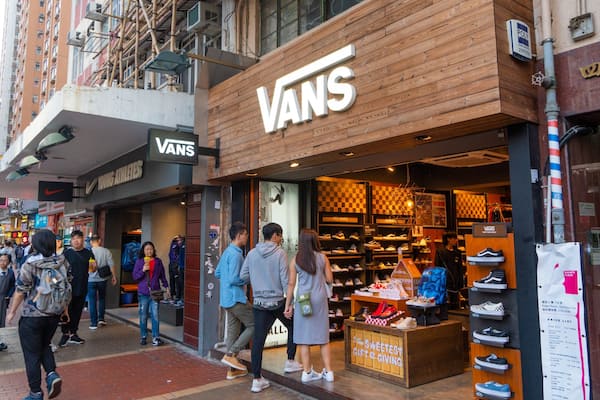 A busy urban street with a prominent Vans store and a Young Athletes shop.