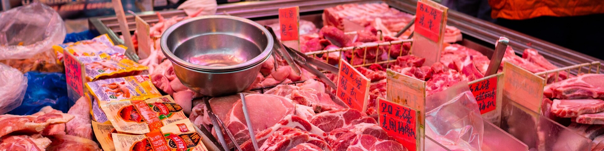 Exposição de carne em um mercado, com diferentes cortes e etiquetas de preço.