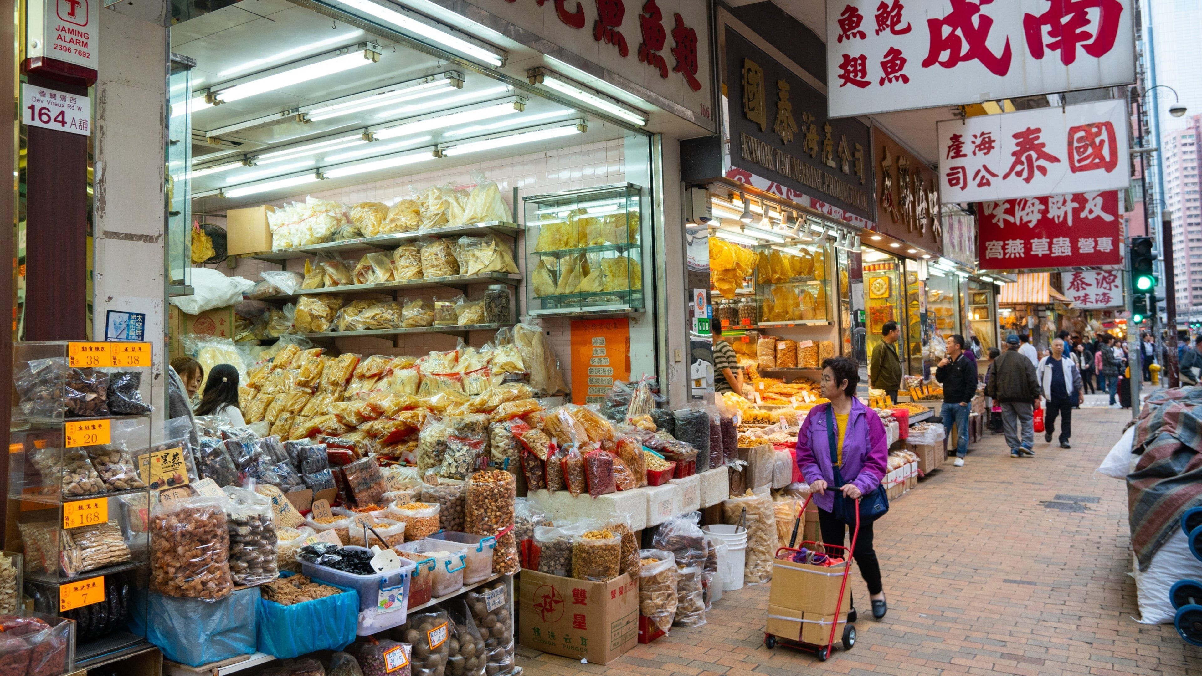 A bustling street market with various food stalls selling dried goods and snacks.