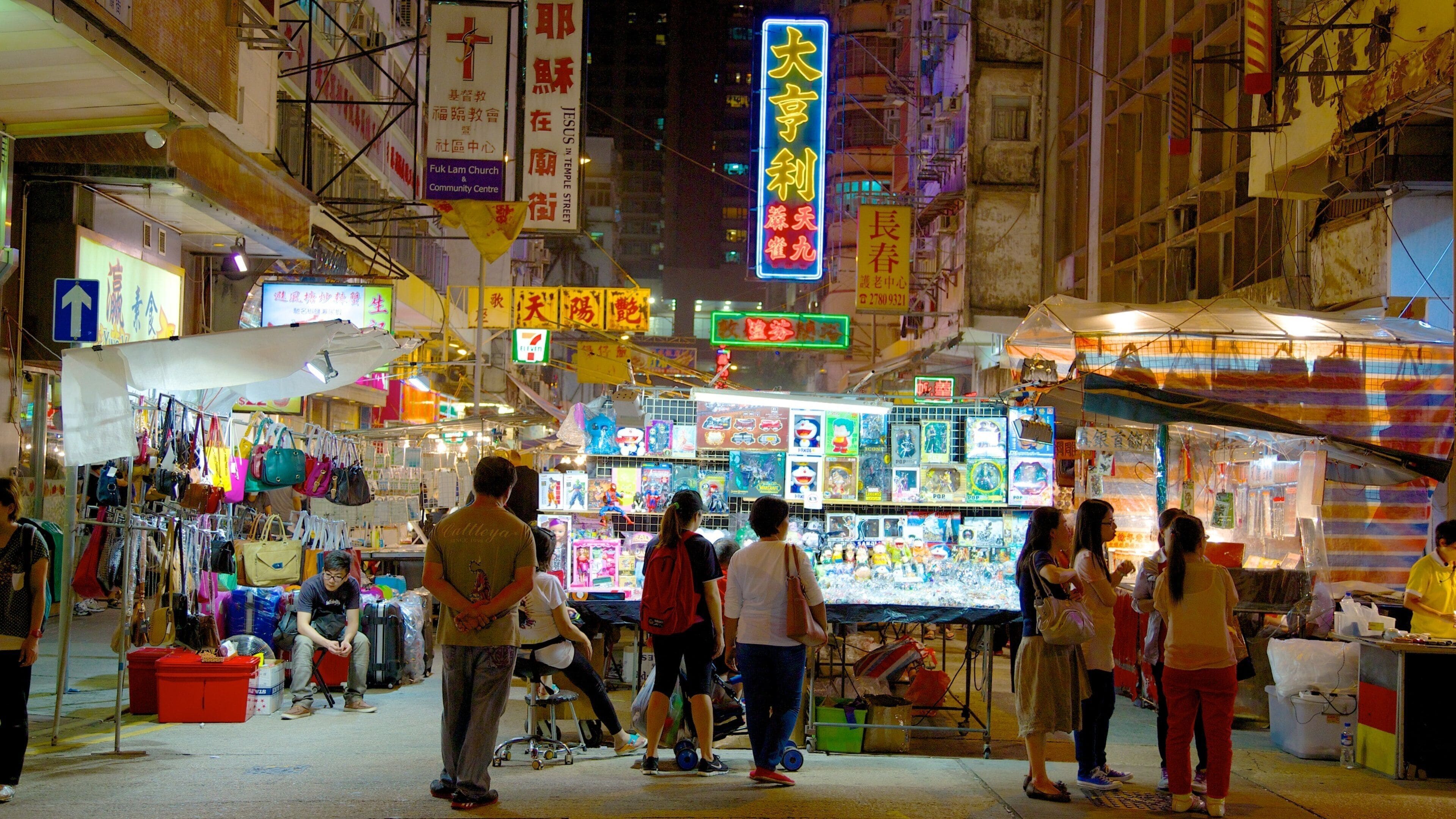 A bustling night market with neon signs and various stalls.
