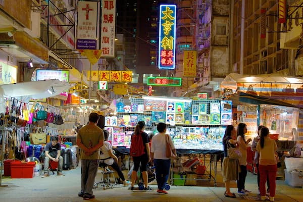 A bustling night market with neon signs and various stalls.