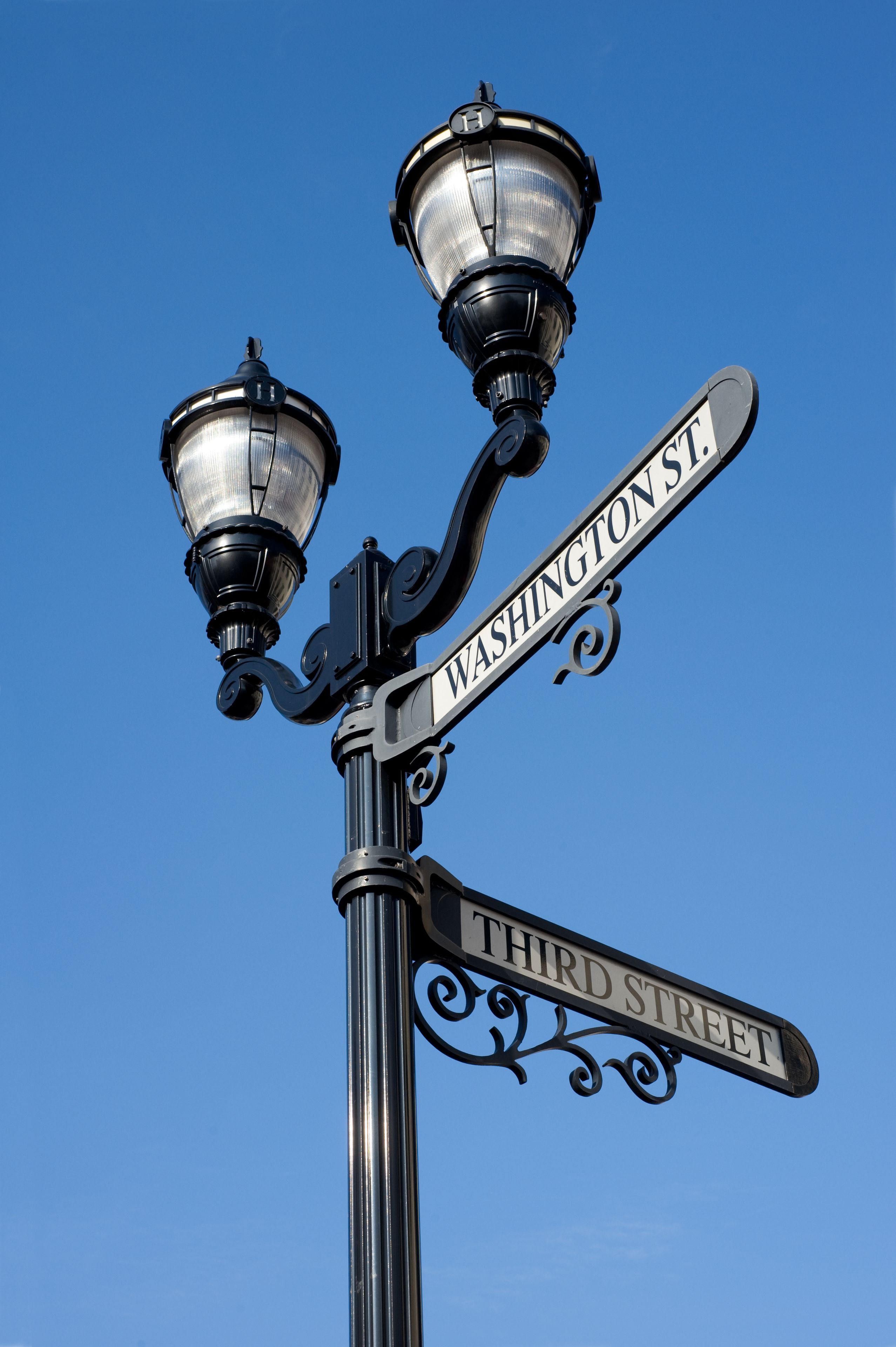 Et vejskilt med 'WASHINGTON ST' og 'THIRD STREET' mod en klar blå himmel.