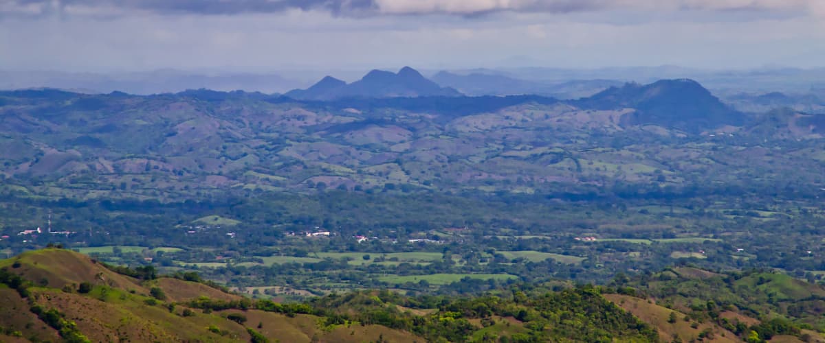 A mountainous landscape with rolling hills and scattered buildings.