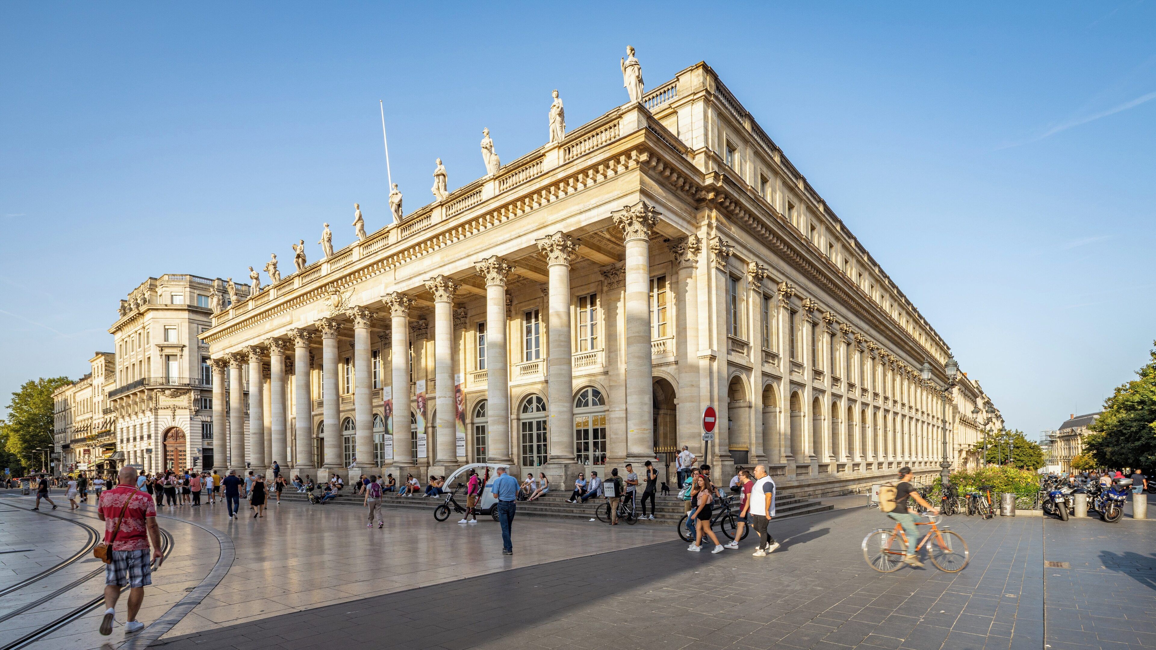 Grand Theatre of Bordeaux stands impressively in city center as visitors explore its grandeur during sunset hours in Nouvelle-Aquitaine