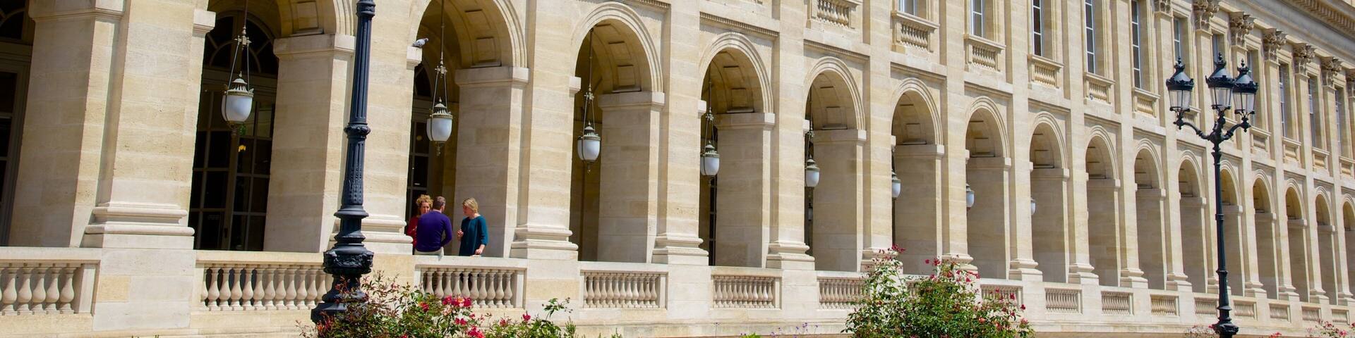Un edificio histórico y majestuoso de arquitectura clásica, con columnas, arcos y farolas decorativas.