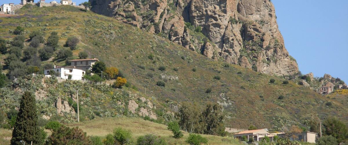 A rocky mountain with a few buildings on its slopes.