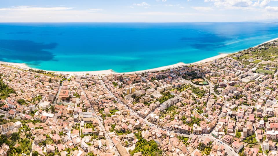 Città di Roccella Ionica in Calabria. Vista aerea del mare Mediterraneo, le case, la strada, la costa e il castello.