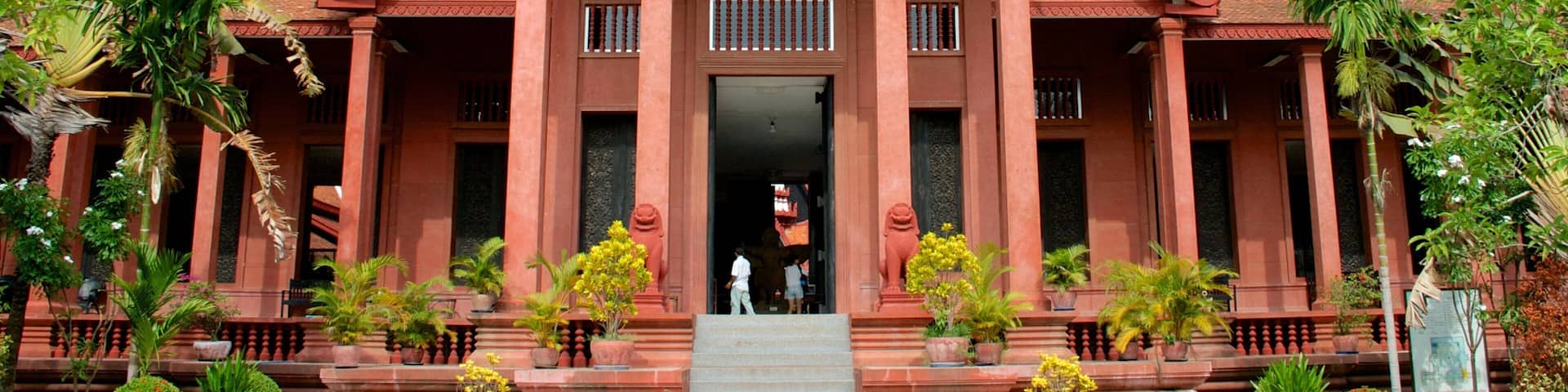 A traditional Thai temple with ornate architecture, a central entrance, and surrounding greenery.