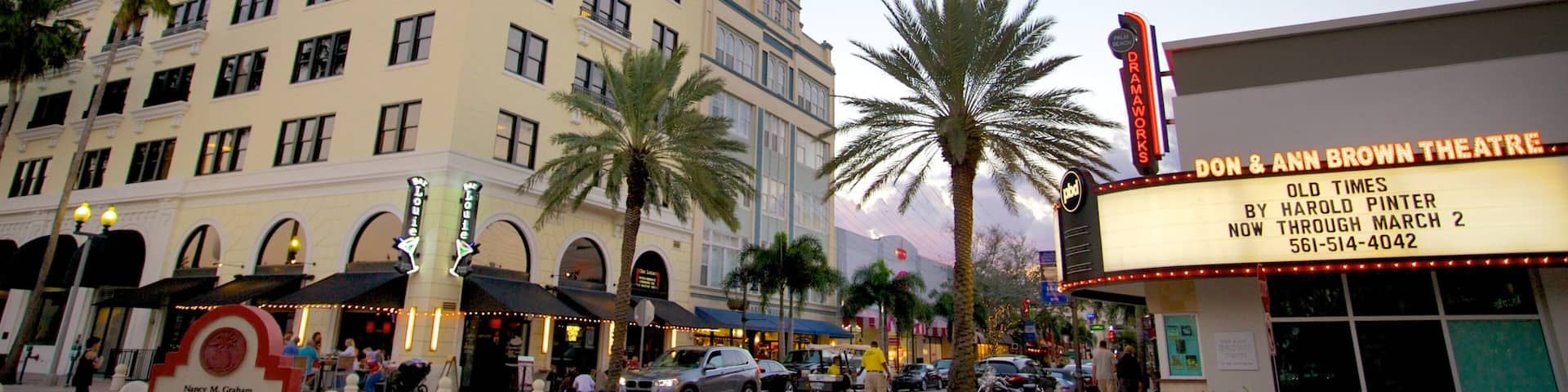 A theater marquee, palm trees, and a multi-story building with arched windows.