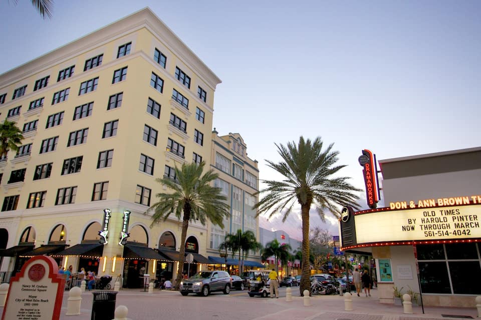 A theater marquee, palm trees, and a multi-story building with arched windows.