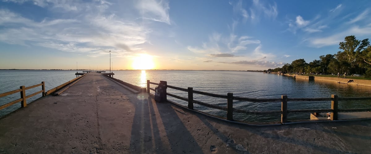 A pier extending into calm waters at sunset with a clear sky.