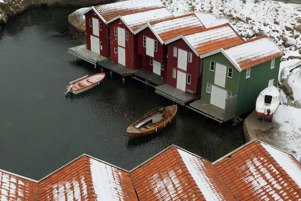 A row of red and green buildings with a dock and boats.
