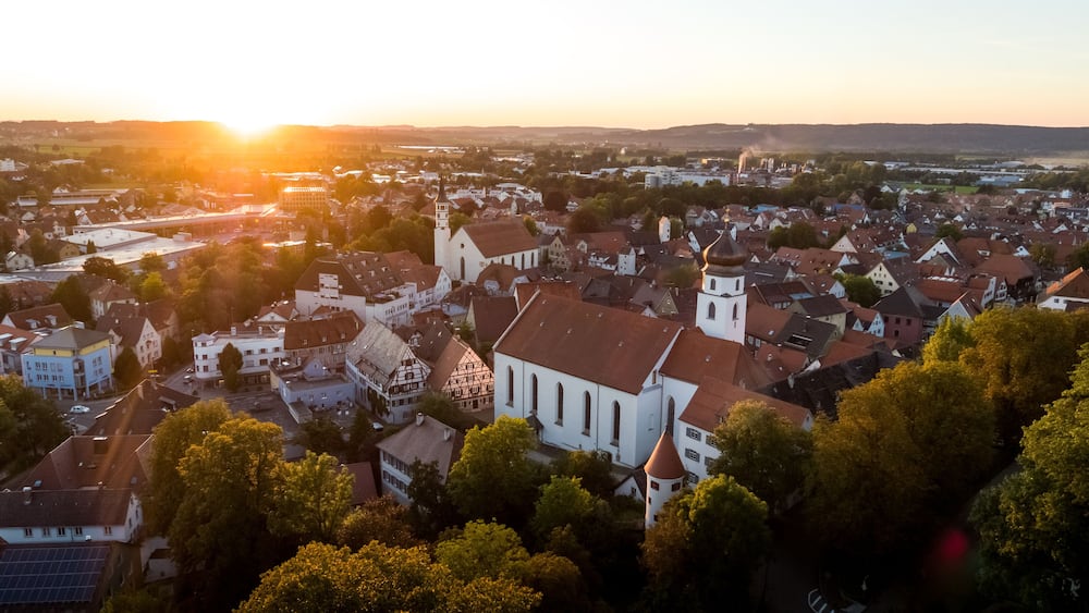Eine Stadt mit einer markanten Kirche, einem Fluss und einem Sonnenuntergang.