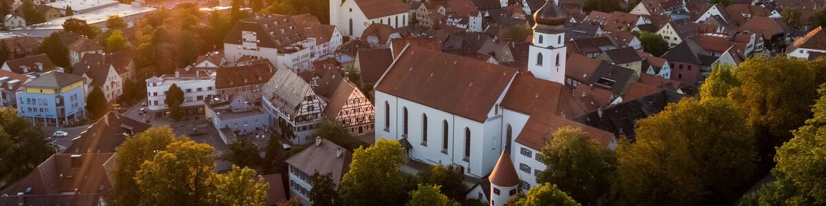 A town with a prominent church, a river, and a sunset.
