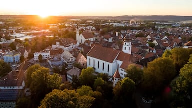 A town with a prominent church, a river, and a sunset.