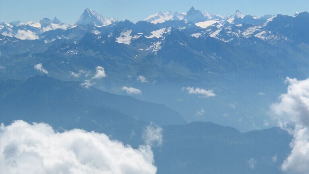 Une chaîne de montagnes aux sommets enneigés, avec une vallée en contrebas.