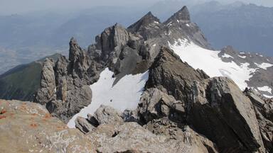 A rugged mountain peak with snow patches and rocky terrain.