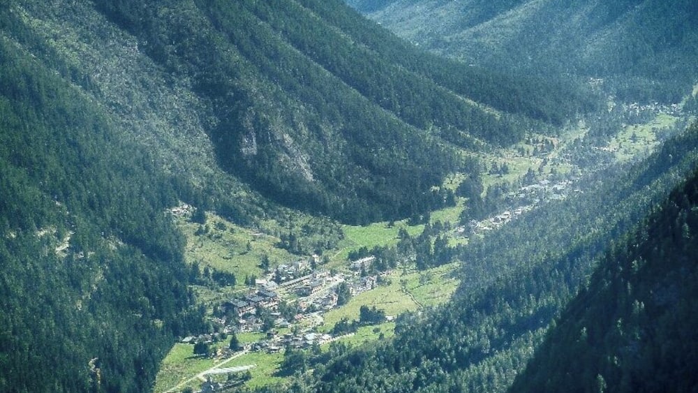 Une vallée où se trouve une petite ville, nichée au milieu de collines verdoyantes et de montagnes.