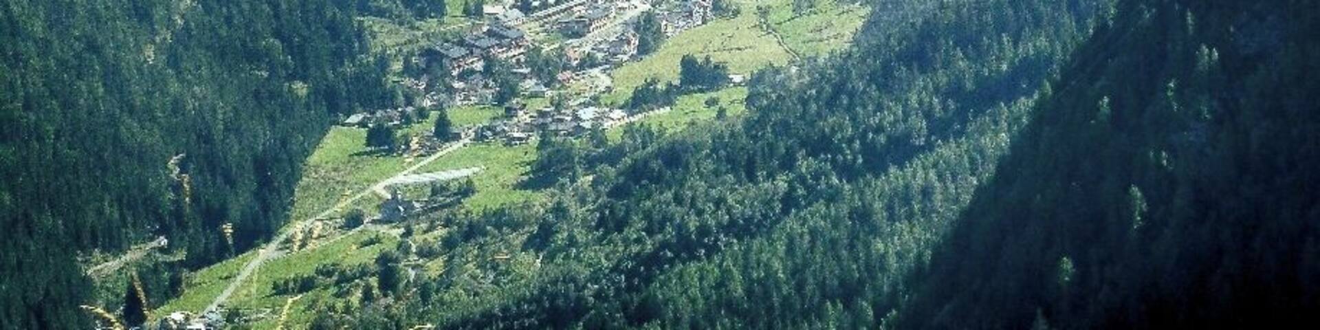 A valley with a small town nestled among green hills and mountains.
