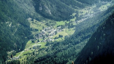 Um vale com uma pequena cidade aninhada entre colinas e montanhas verdes.