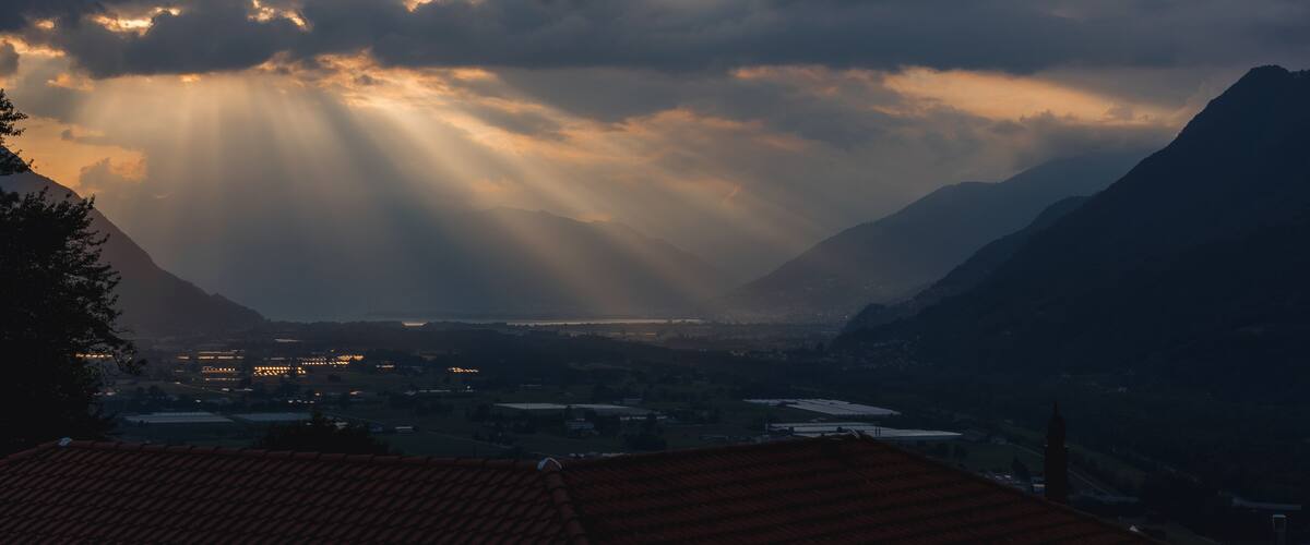 A mountainous landscape with a valley and a distant body of water.