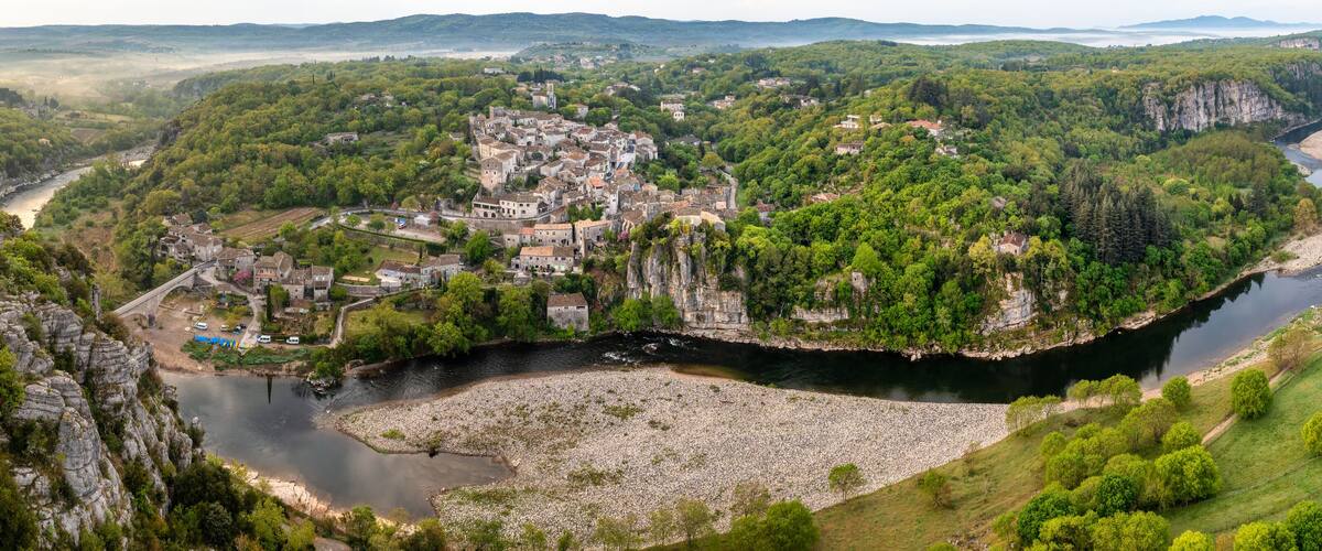 A river winding through a valley with a town on a cliff.