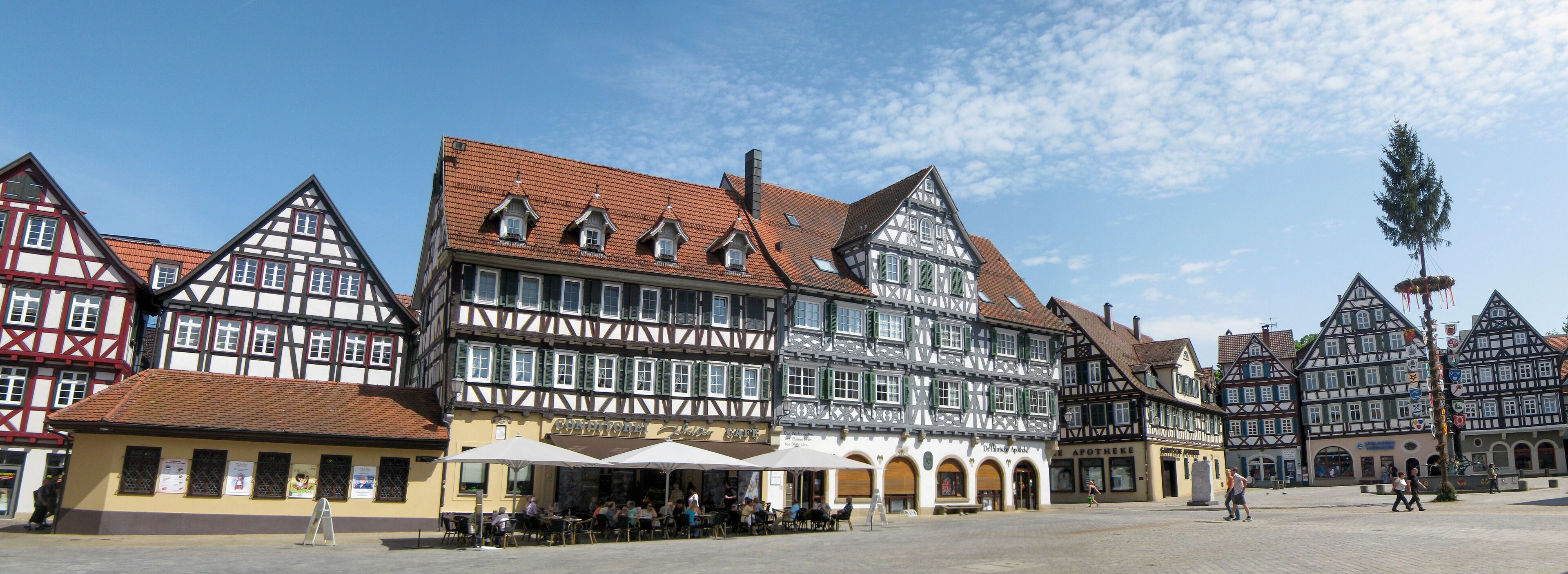 A traditional European town square with half-timbered buildings and outdoor seating areas.