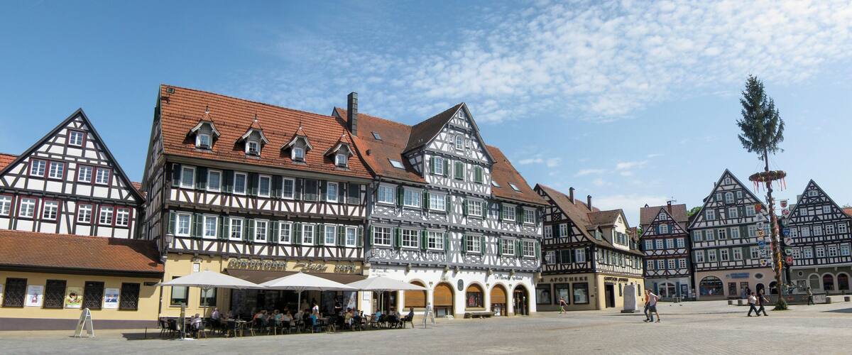 A traditional European town square with half-timbered buildings and outdoor seating areas.