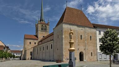 A historic church with a tall spire and a statue in front.