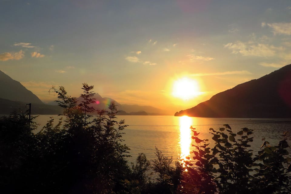 A sunset over a lake with mountains in the background.