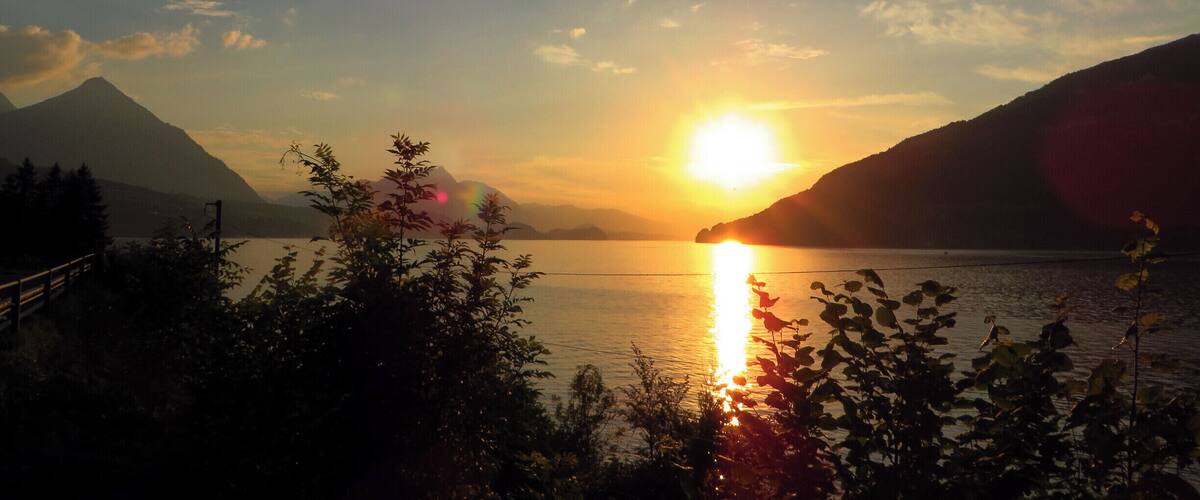 A sunset over a lake with mountains in the background.