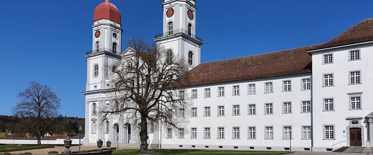 A white building with two red domes and a clock tower.