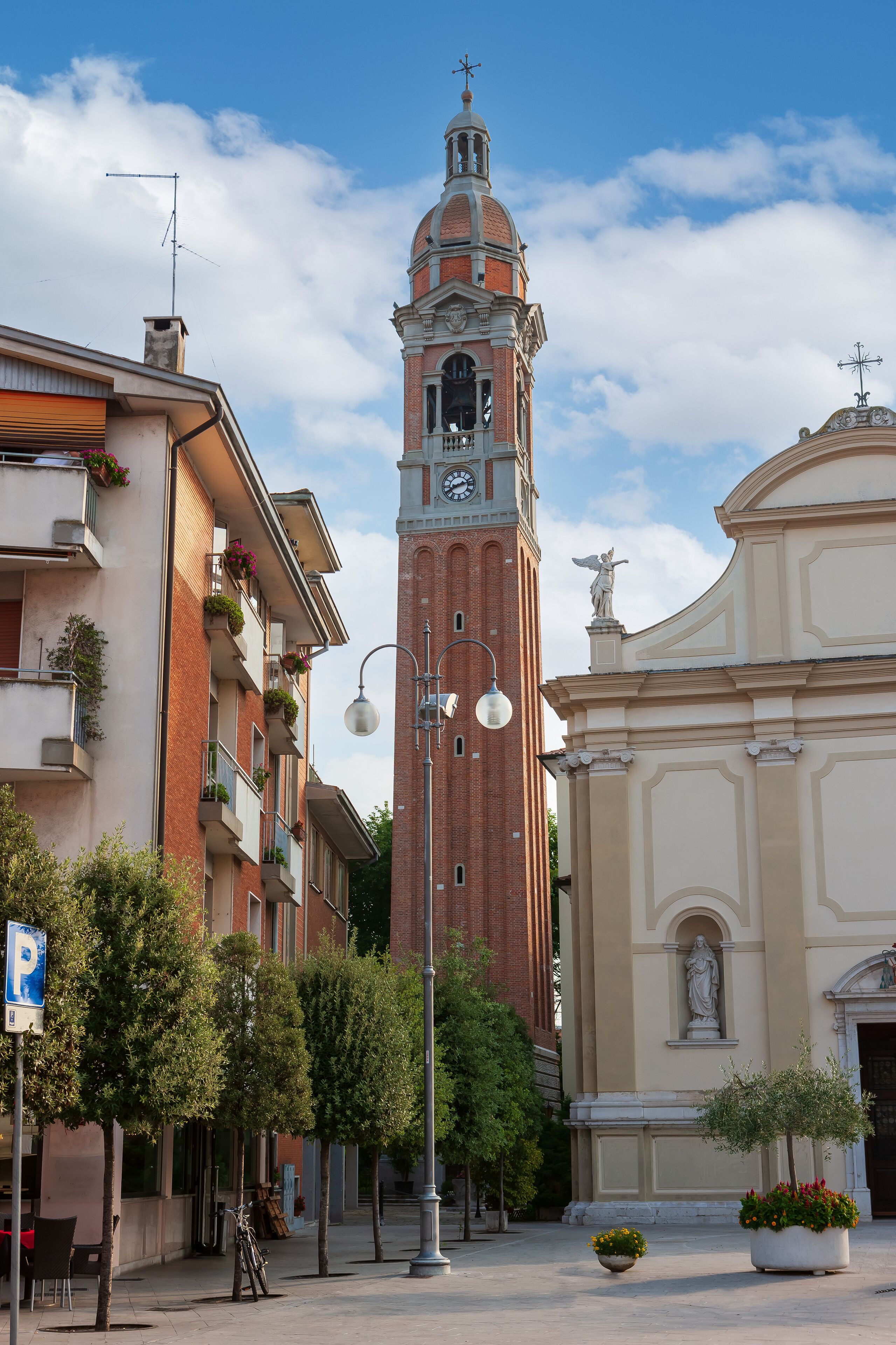 A historic tower with a clock, surrounded by buildings and trees.