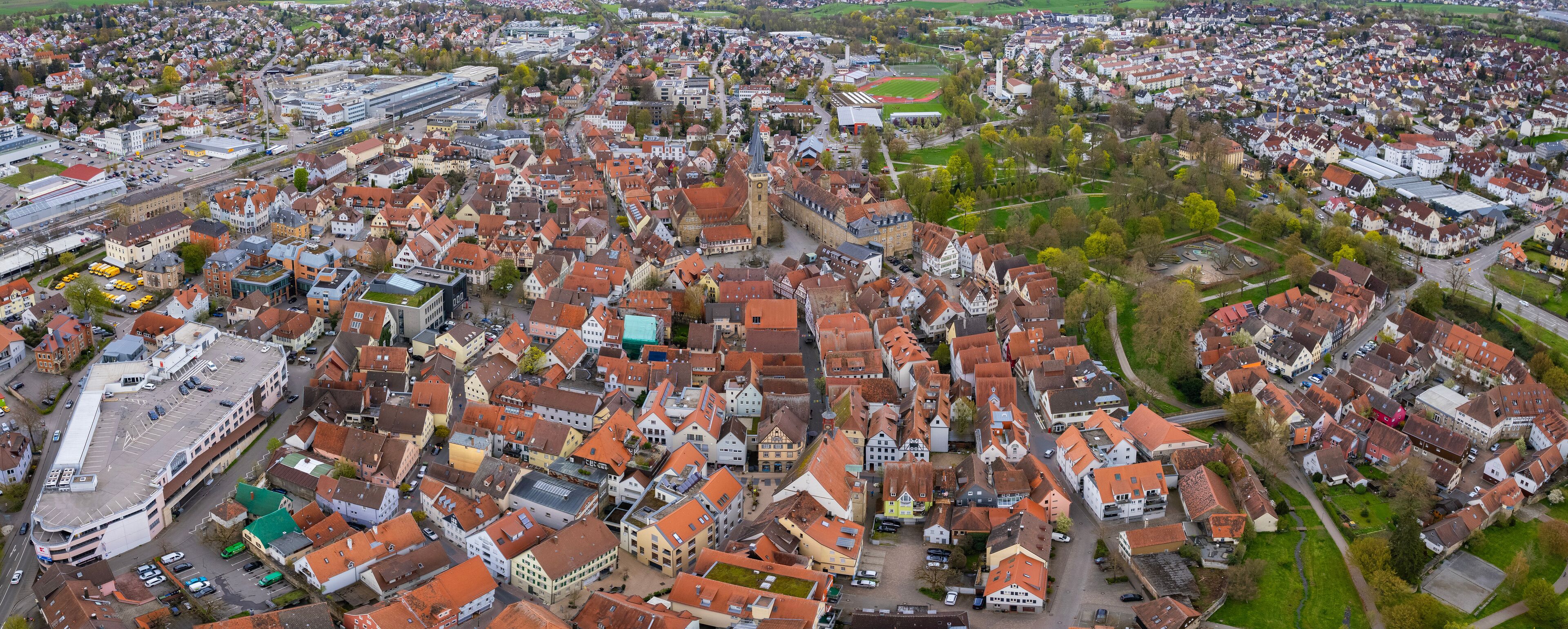An aerial view of a densely packed town with historic buildings and a prominent church tower.