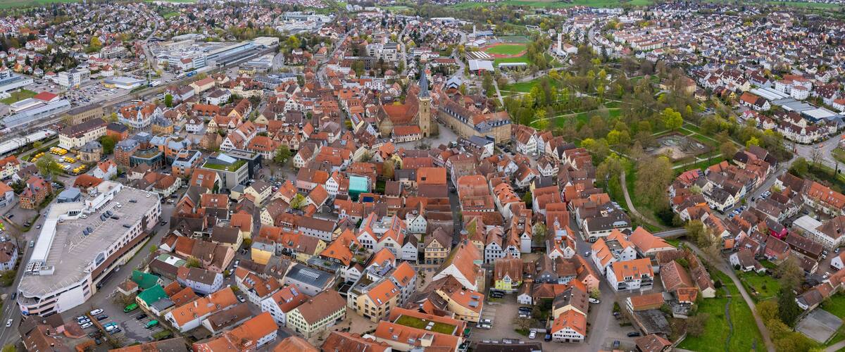 An aerial view of a densely packed town with historic buildings and a prominent church tower.