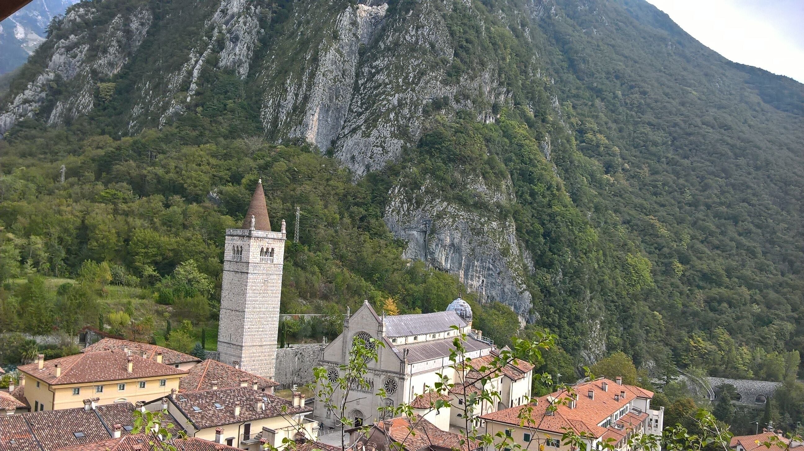 A mountainous landscape with a church featuring a tall bell tower and a dome.