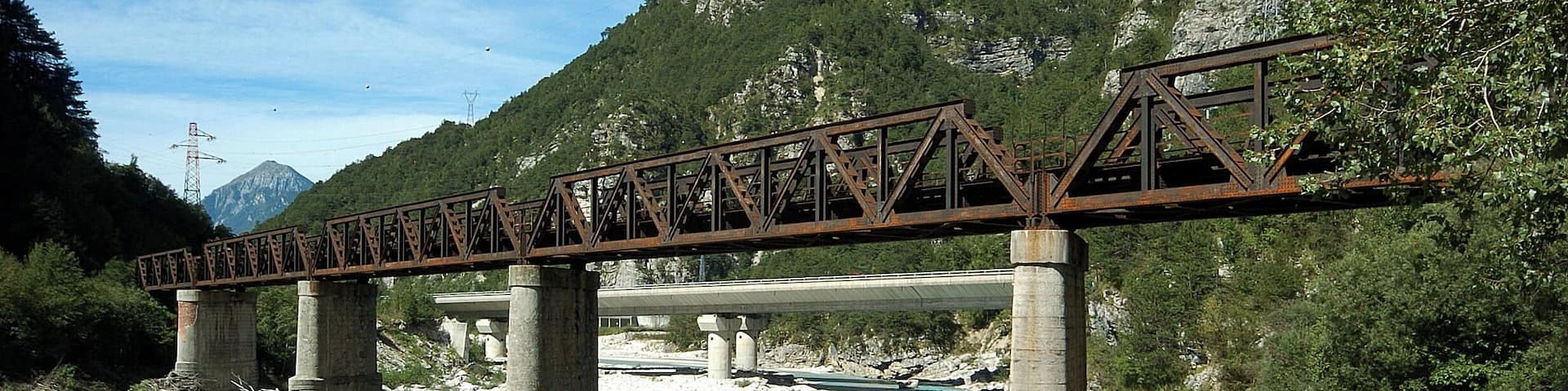 Railroad bridge across the river Fella, part of a defunct railroad line called the old "Pontebbana", in the north-eastern part of Italy, region Friuli Venezia-Giulia. In the background there are the two bridges of the Autostrada Alpe-Adria.