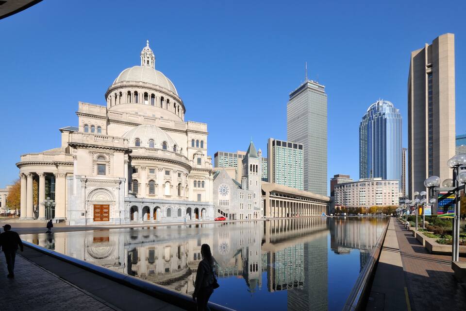 A historic building with a dome, a modern skyscraper, and a reflective water body.